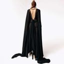 Back view of Caitlin facing away from  camera while wearing the Dark Angel Chiffon Sheer Maxi Dress with billowing draping floor-length sleeves from SCATHED's Fall Winter 2025 Reaper collection.