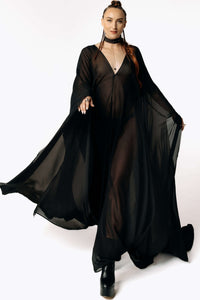 Front view of Caitlin walking toward camera while wearing the Dark Angel Chiffon Sheer Maxi Dress with billowing draping wide sleeves from SCATHED's Fall Winter 2025 Reaper collection.