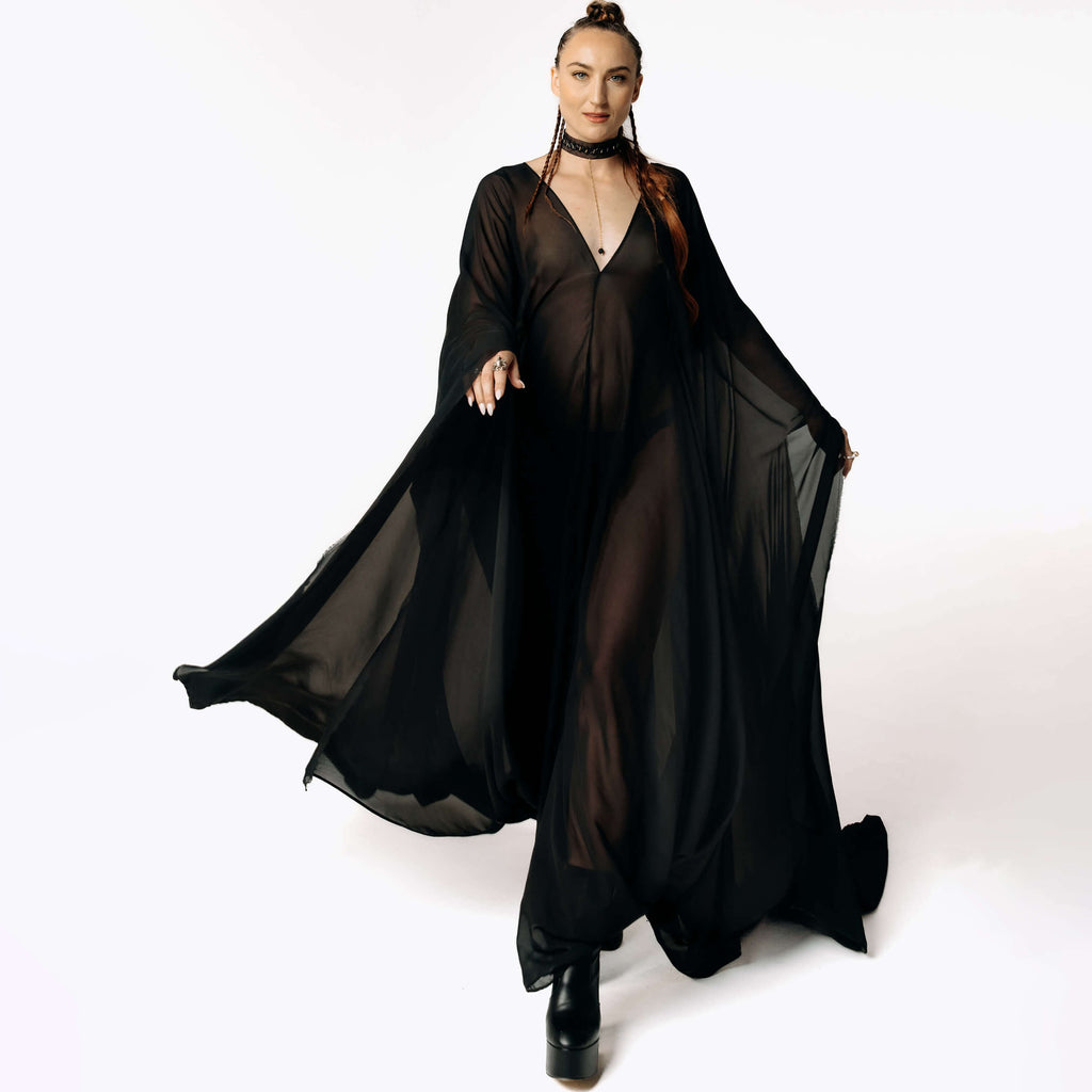 Front view of Caitlin walking toward camera while wearing the Dark Angel Chiffon Sheer Maxi Dress with billowing draping wide sleeves from SCATHED's Fall Winter 2025 Reaper collection.