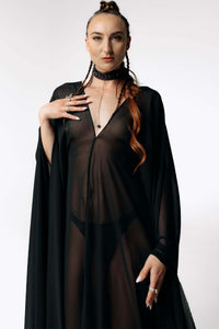 Front portrait view of Caitlin standing facing  camera while wearing the Dark Angel Chiffon Sheer Maxi Dress with billowing draping wide sleeves from SCATHED's Fall Winter 2025 Reaper collection.