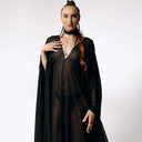 Front portrait view of Caitlin standing facing  camera while wearing the Dark Angel Chiffon Sheer Maxi Dress with billowing draping wide sleeves from SCATHED's Fall Winter 2025 Reaper collection.