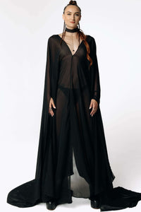 Front view of Caitlin standing facing  camera while wearing the Dark Angel Chiffon Sheer Maxi Dress with billowing draping wide sleeves from SCATHED's Fall Winter 2025 Reaper collection.