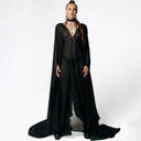 Front view of Caitlin standing facing  camera while wearing the Dark Angel Chiffon Sheer Maxi Dress with billowing draping wide sleeves from SCATHED's Fall Winter 2025 Reaper collection.
