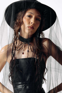 Person wearing a black outfit with a veil on a white background