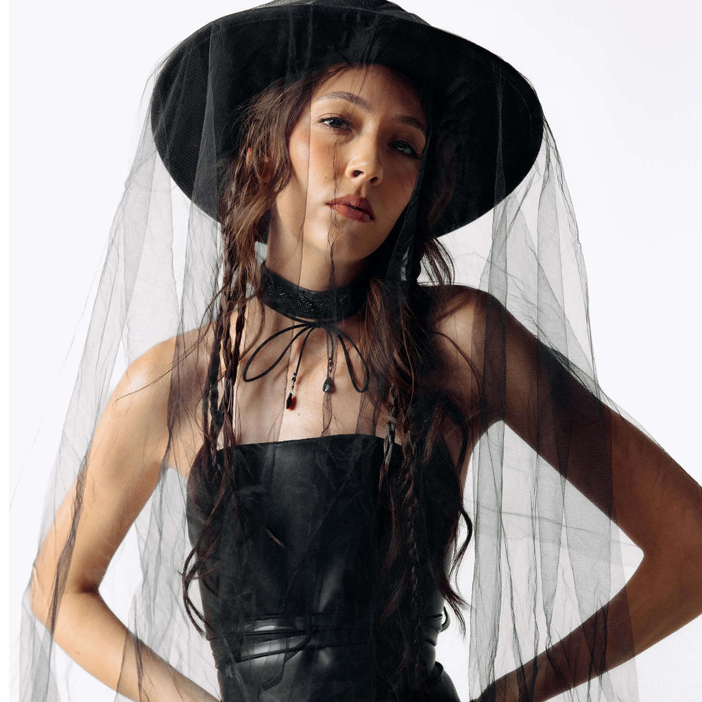 Person wearing a black outfit with a veil on a white background
