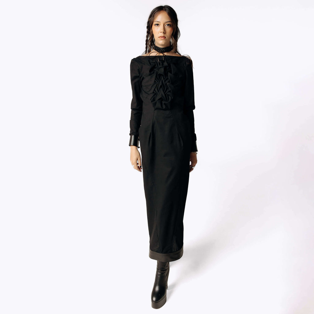 Frontal view of Eliza wearing the Mors Black Cotton Dress with ruffling in the chest from SCATHED's Fall Winter 2025 Reaper collection. Eliza also wears black high-heeled platform boots while stepping towards frame.