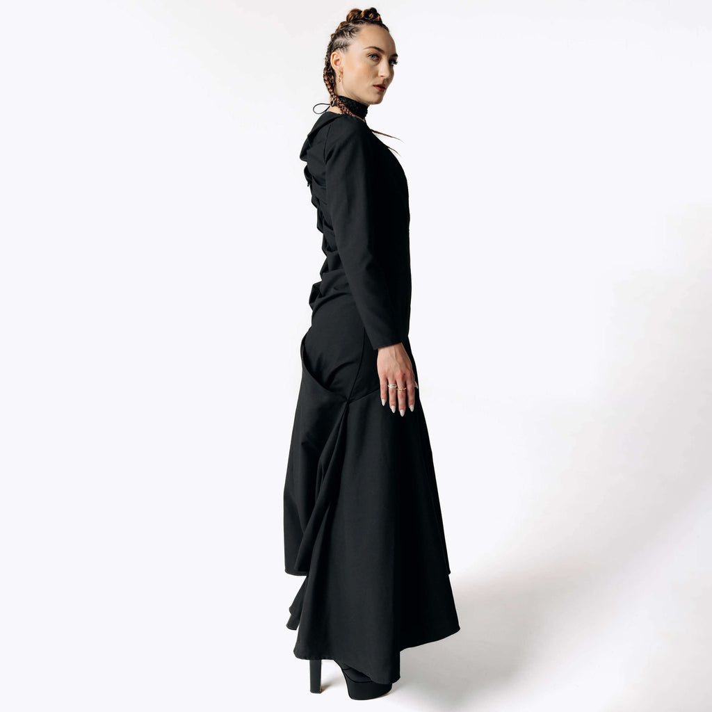 Side view of Caitlin facing camera while wearing the Nox Black Cotton Skeleton Dress from SCATHED's Fall Winter 2025 Reaper collection.