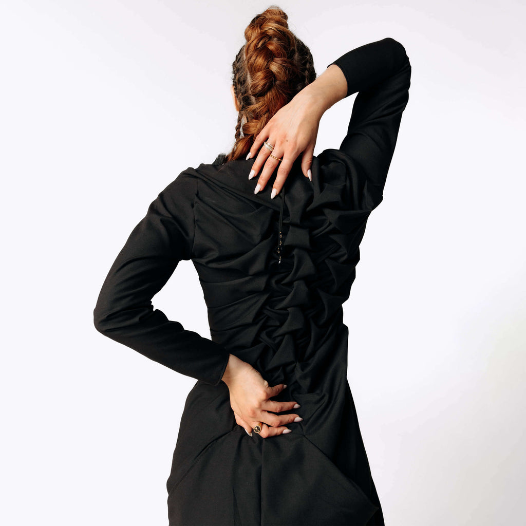 Close-up back view of Caitlin with braided hair wearing the Nox Black Cotton Skeleton Dress with a ruffled spinal texture from SCATHED's Fall Winter 2025 Reaper collection.