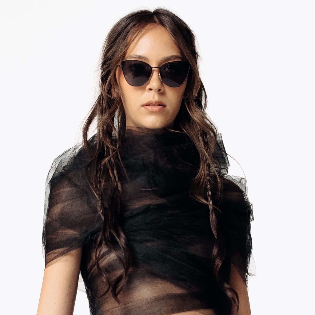Image of Eliza wearing the Venin Black sunglasses while facing the camera wearing the black sheer Mot Tulle Cloud Blouse from SCATHED's Fall Winter 2025 Reaper collection.