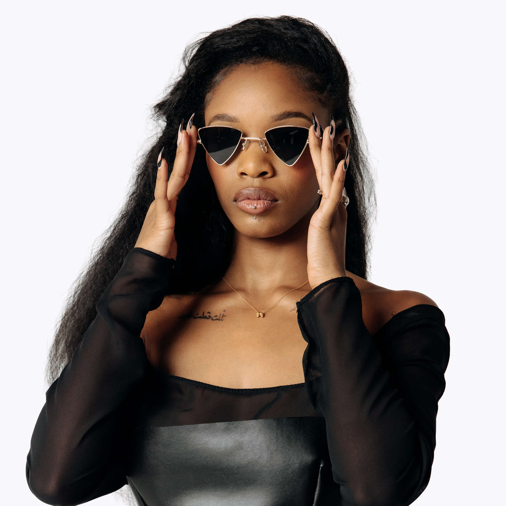 Image of Eliza wearing the Vex Black sunglasses while facing the camera wearing the black sheer Samhanach Chiffon Gown from SCATHED's Fall Winter 2025 Reaper collection.