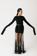 Video of model showing black long sleeve shirt styled with a sheer hand beaded skirt showing front side and back view