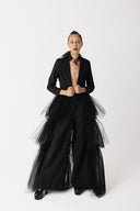 Model wears black cotton blazer with eco tulle train. She wears it with cotton wide leg pants. Shows front view, side view, back view, and close up.