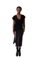 A model stands in a studio wearing a black t-shirt top with short cap sleeves and low v neck, a matching black skirt with a front slit, and black ankle boots.