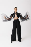 Model wearing black cactus leather cropped bolero jacket with sheer tulle balloon sleeves, arms outstretched, front view
