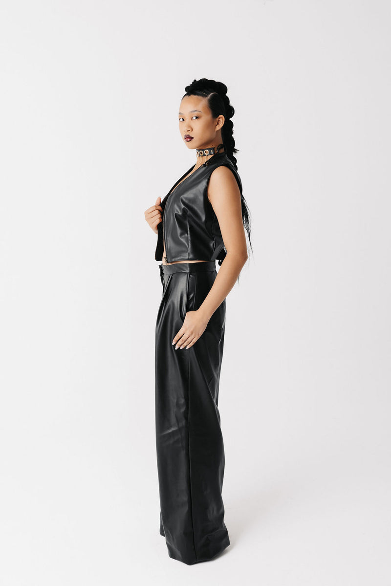Model wearing black cactus leather zip-front vest, open, with matching wide-leg trousers, side view