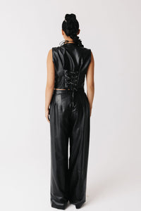 A model viewed from the back wearing a black cactus-leather sleeveless top and matching wide-leg pants with a lace-up back detail, set against a plain white studio background.