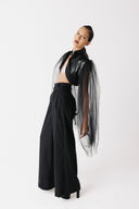 Side view of model wearing black cactus leather bolero jacket with sheer tulle sleeves and wide-leg trousers