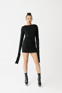 Model wearing black jersey top with extra-long sleeves and boat neckline, styled as a mini dress