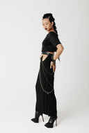 Side view of the Penance Skirt showing hip cutouts, O-ring hardware, and crossing gold chains