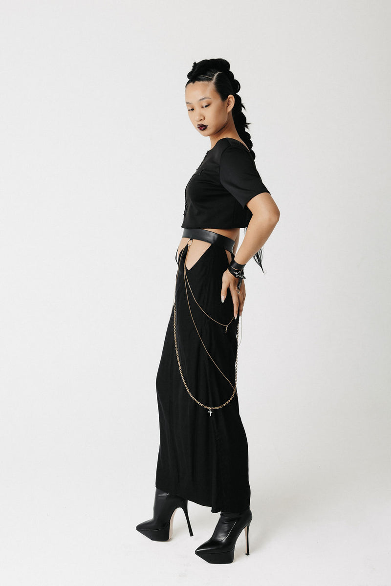 Side view of the Penance Skirt showing hip cutouts, O-ring hardware, and crossing gold chains