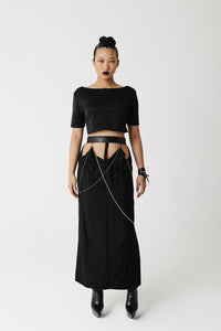 Model wearing the Penance Skirt, an organic bamboo cotton maxi skirt with cactus leather waistband and draped gold chains