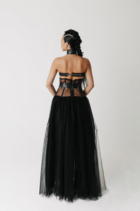 Model wearing The Tomyris Skirt, a black eco-tulle skirt with boned corset waistband back view