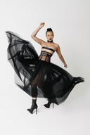 Model wearing The Tomyris Skirt, a black eco-tulle skirt with boned corset waistband, tulle spread in motion