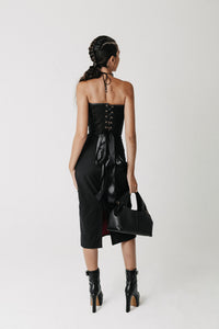 Back view of the Solace Skirt showing its longer hem and back slit. Worn with black lace up corset