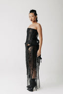 Side view of model wearing the Boudica Gown, a strapless corset dress with hand-beaded fringe cascading down the front