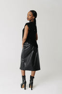 Back view of model wearing the Sever Skirt, a cactus leather midi skirt with dual front zippers, both closed