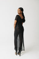 Model wearing black hand-beaded sheer chiffon gown, full length, with platform boots. Showing beading on back of dress.